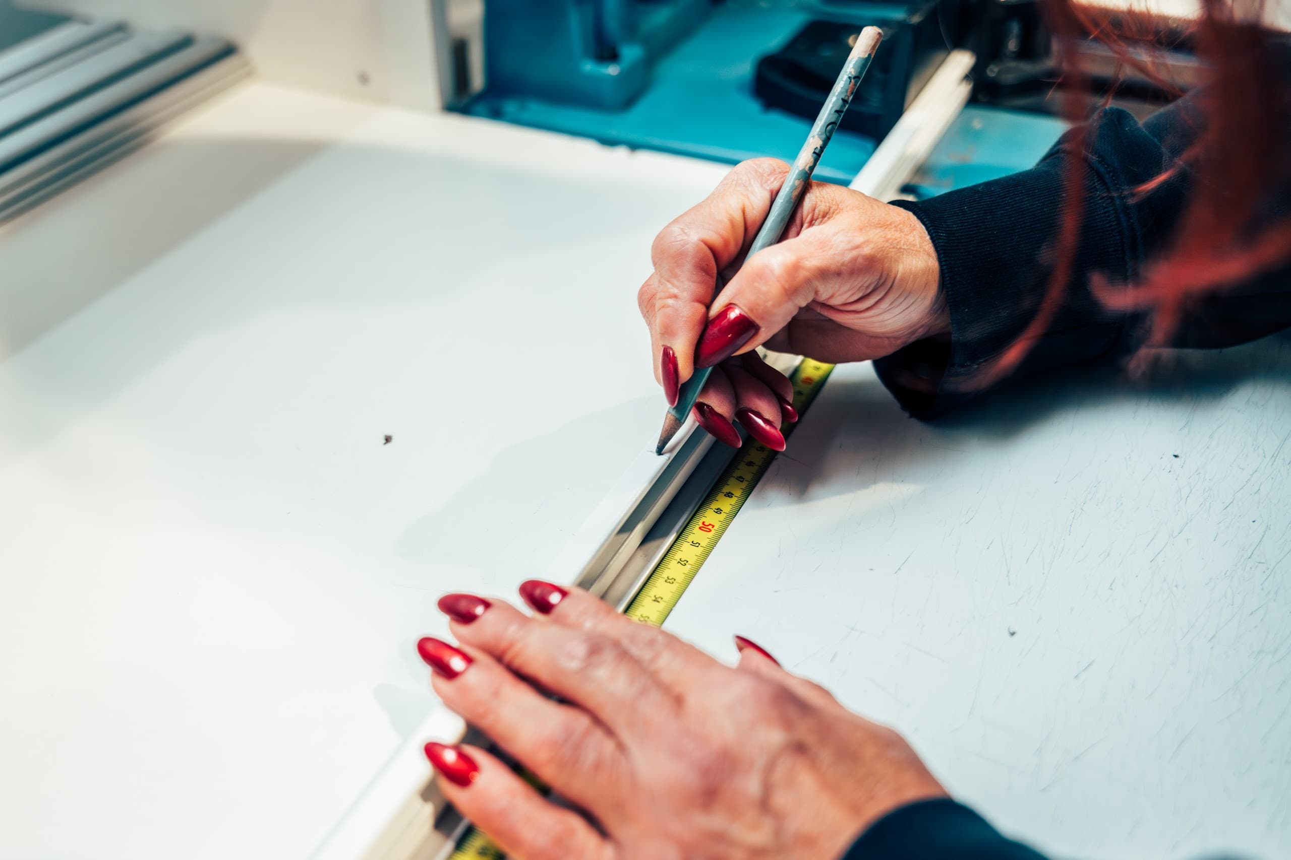 Medewerker die stof opmeet en versnijdt in het atelier van Lian.
