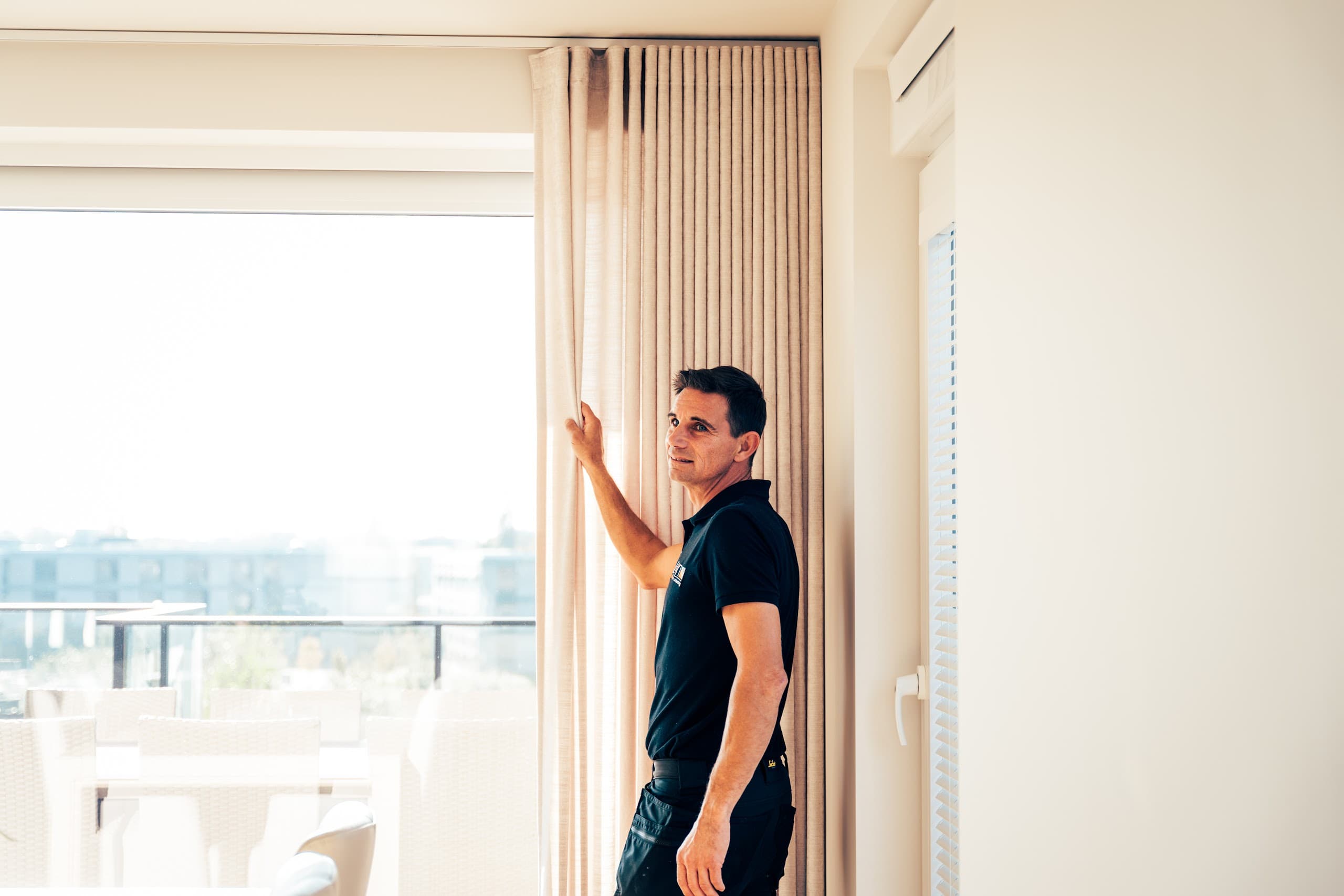 Medewerker van Lian hangt een gordijn op in een appartement