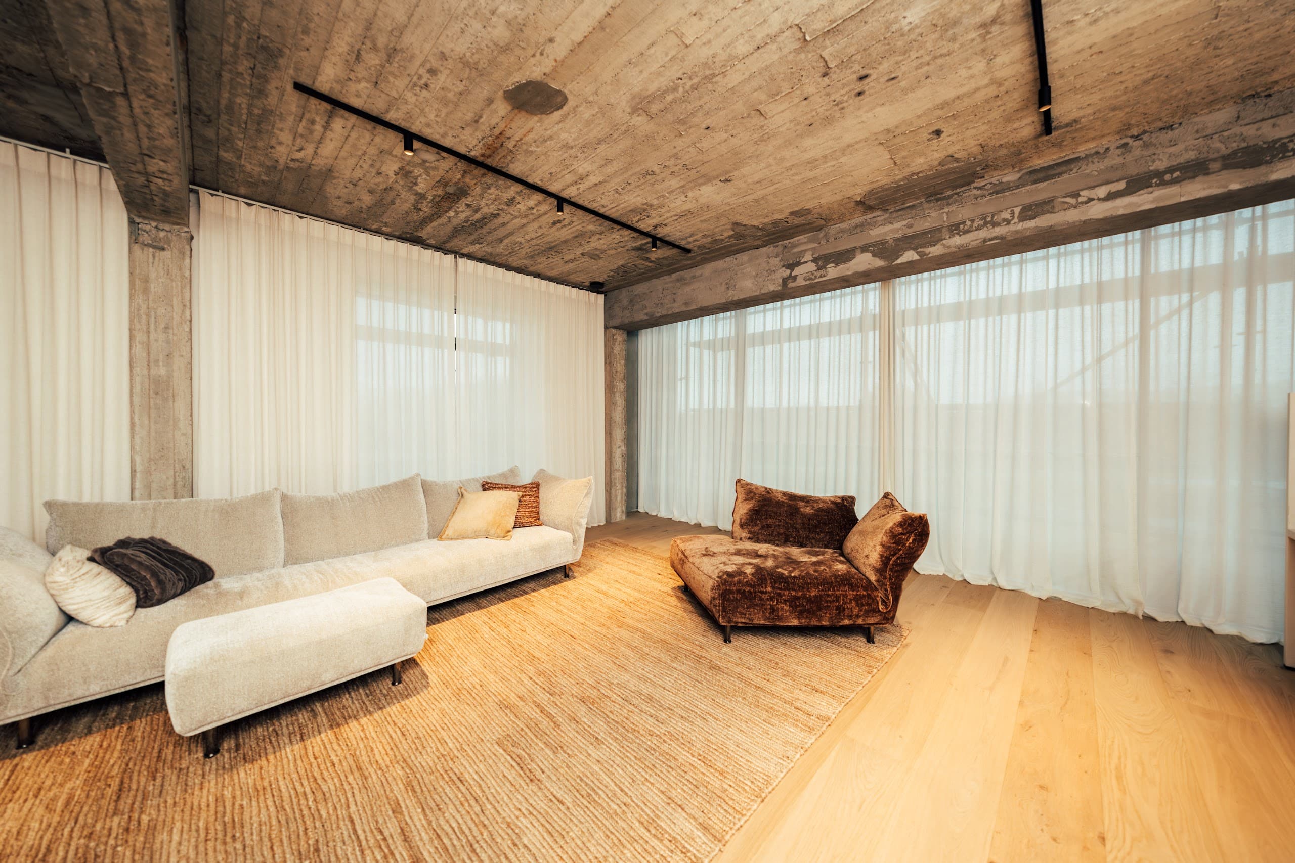 Industriële loft met betonnen plafond, houten vloer en transparante gordijnen