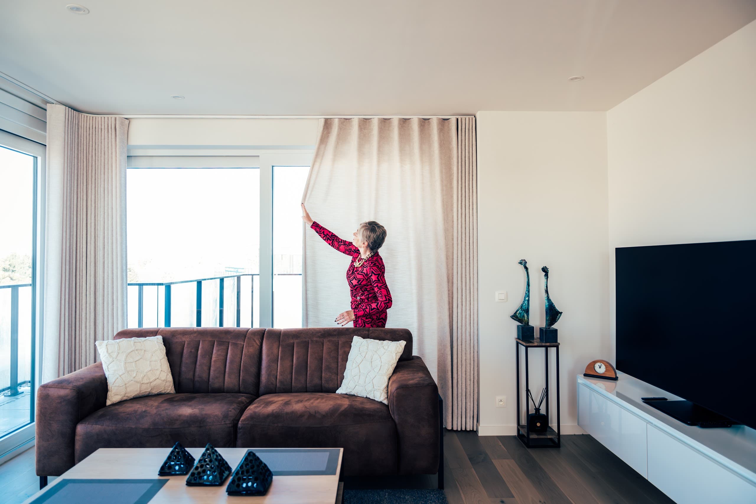 Moderne woonkamer met loungebank en lichte gordijnen langs de raampartij