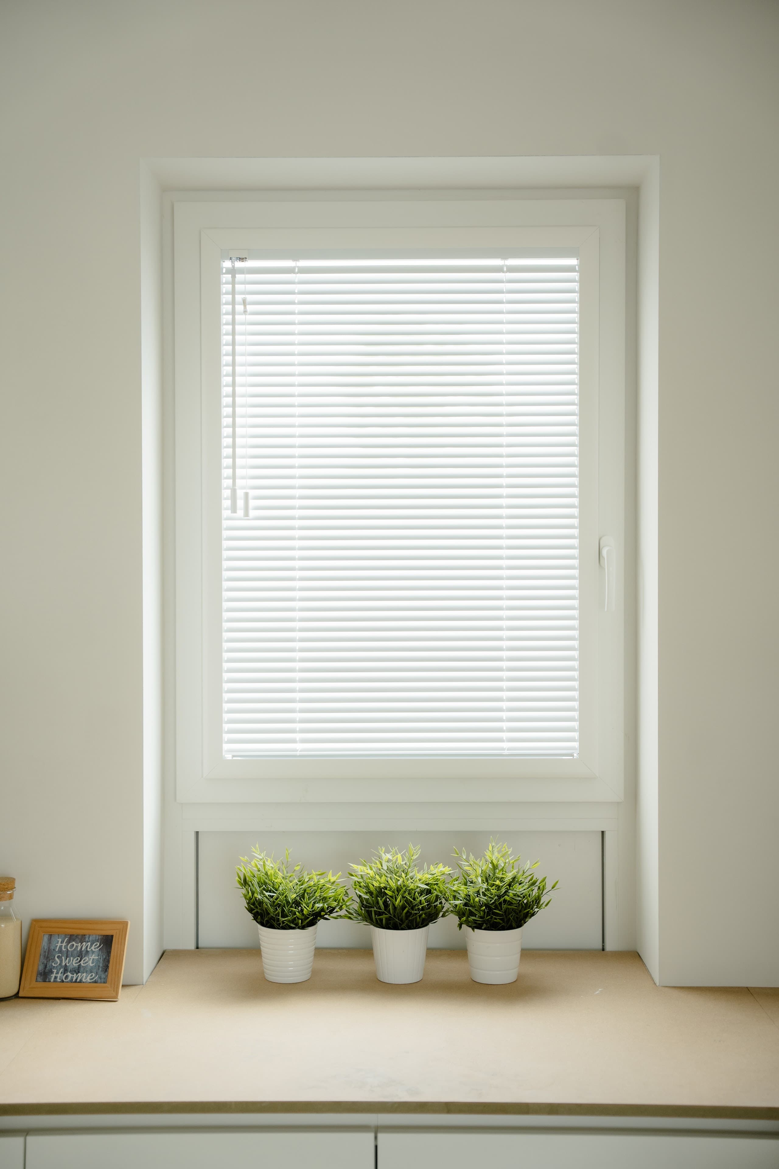 Raam met witte horizontale lamellen die het daglicht zacht temperen