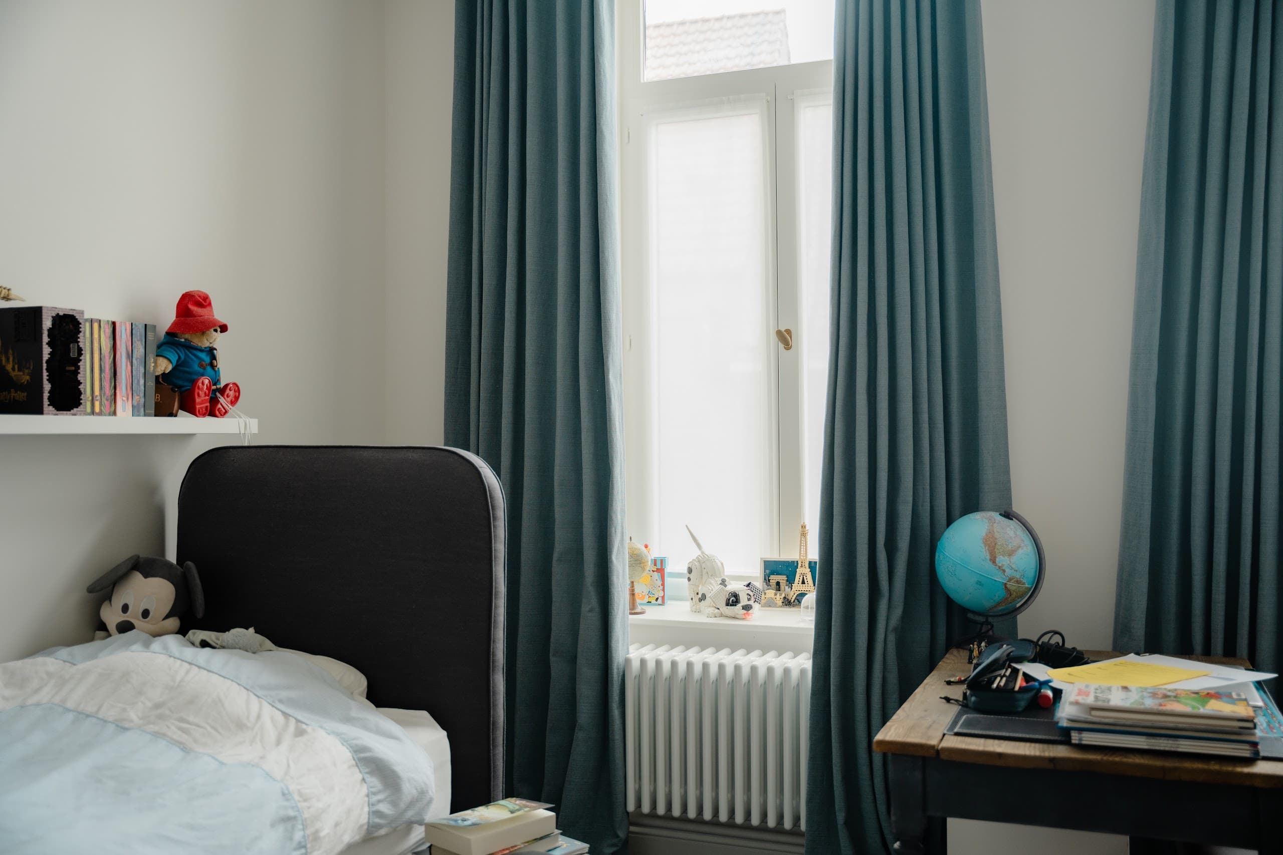 Kinderkamer met tealkleurige overgordijnen langs het raam