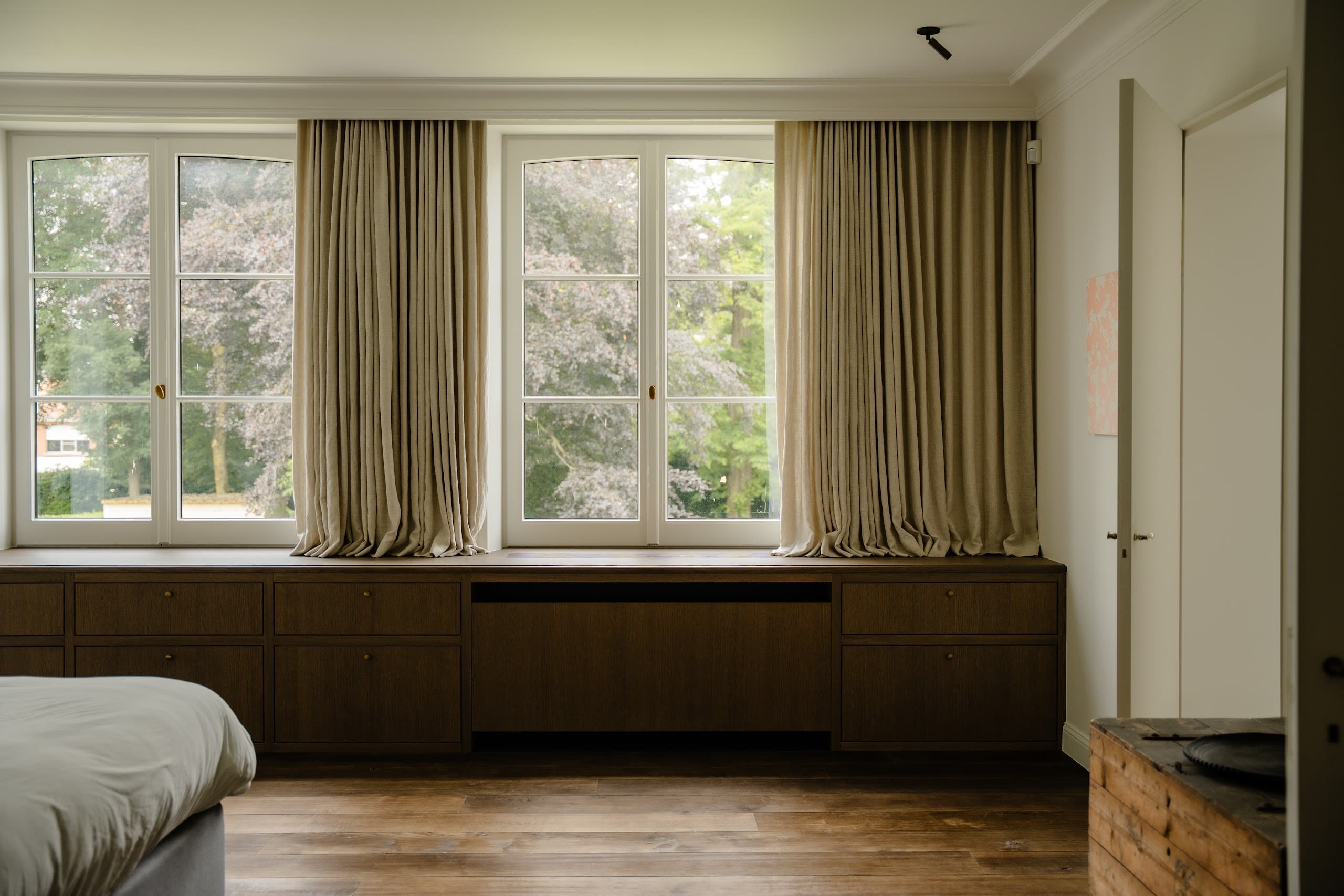 Slaapkamer met overgordijnen en zicht op de tuin