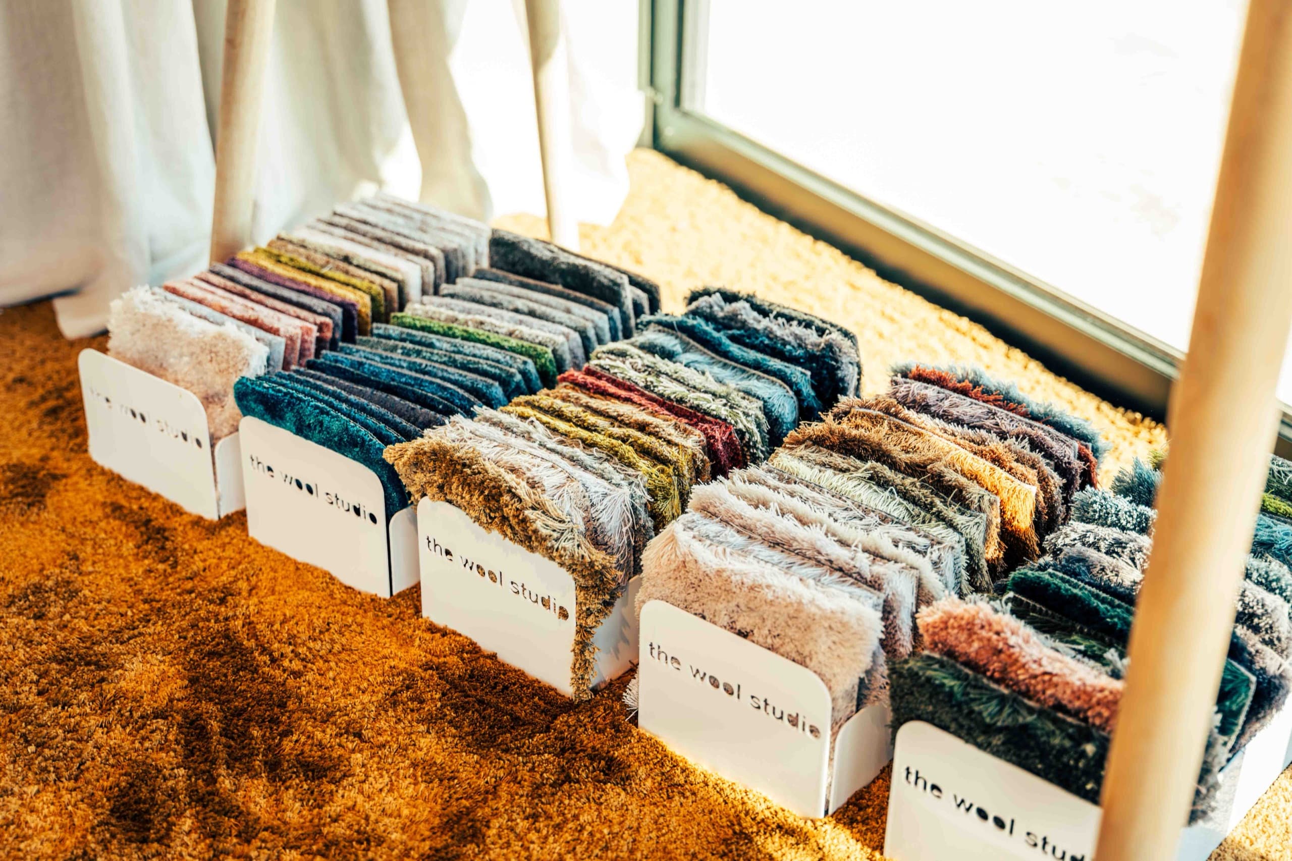Tapijtstalen in verschillende kleuren en structuren op een okerkleurig tapijt